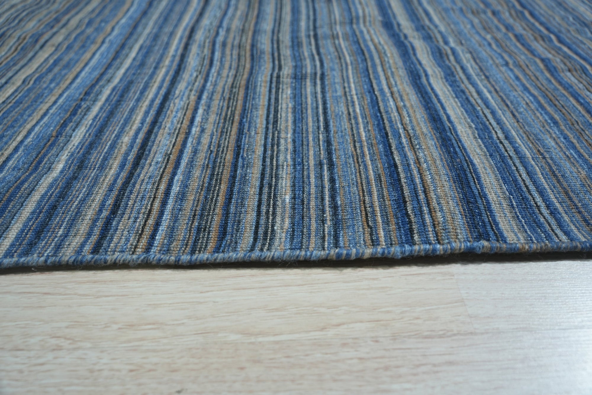 Freya Alluring Blue Handmade Rug displayed in a well-lit room, its intricate design and cool blue tones adding a sophisticated touch to the space.