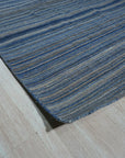 Freya Alluring Blue Handmade Rug, a blend of cerulean and indigo hues, lies gracefully on a polished wood floor, its intricate hand-knotted construction hinting at timeless elegance.