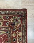 Lydia Vibrant Red Hand Tufted Wool Rug anchors a modern living room. Its vibrant red wool construction radiates warmth against a light wooden floor, surrounded by neutral furniture.