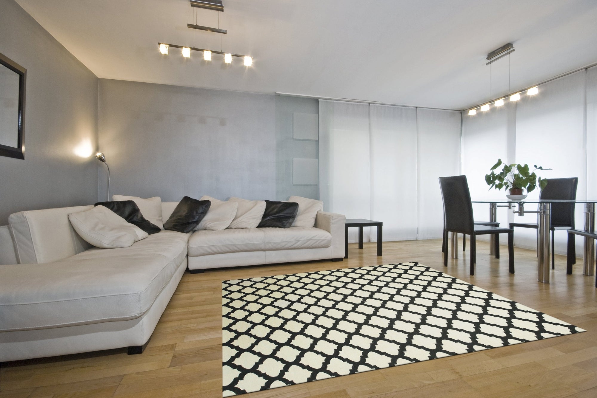 Maya Moroccan Black Flatweave Wool Rug, a striking geometric pattern in bold black against a light background, lies flat in a well-lit living space, adding a modern tribal touch to the room's decor.