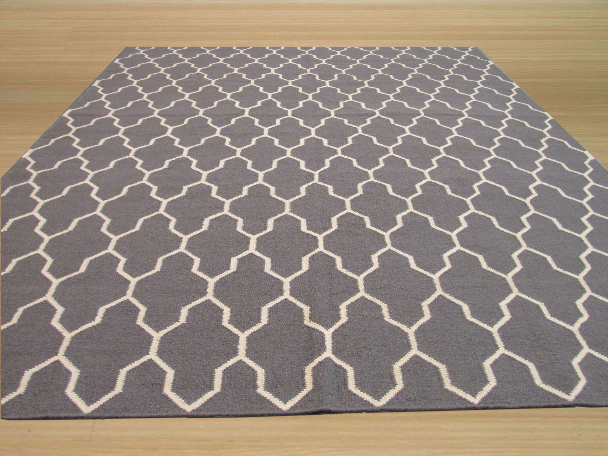 Classic Moroccan Gray Flatweave Wool Rug displayed in a living room setting. Soft gray wool forms a geometric pattern across the flatweave rug, contrasting subtly with the light hardwood floor. The rug anchors a seating area, lending a touch of understated Moroccan style.