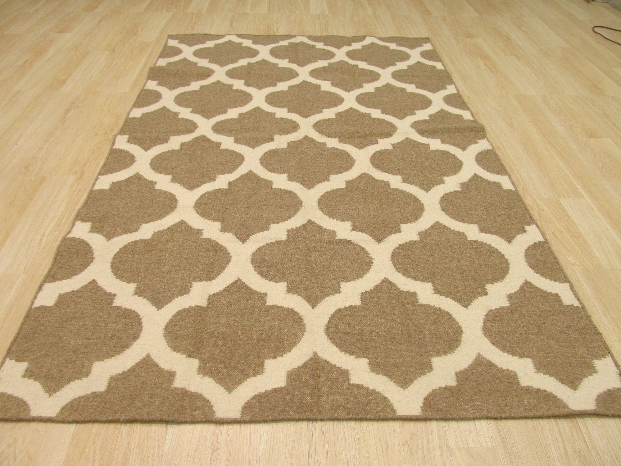 Iris Moroccan Brown Flatweave Wool Rug, woven in a neutral living space, showcasing its intricate geometric pattern in shades of brown and cream.