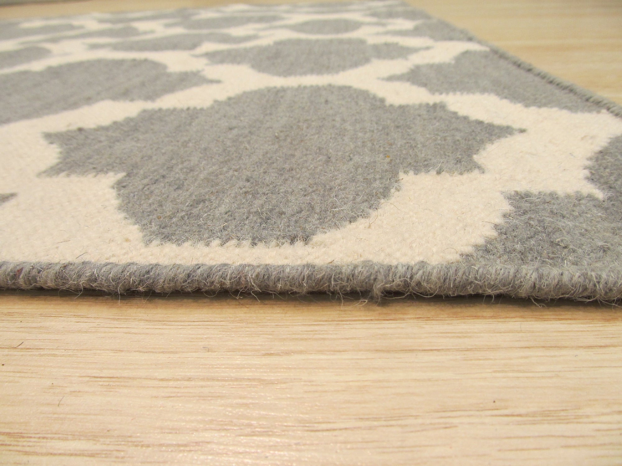 Selene Elena Gray Flatweave Wool Rug, subtly textured and light gray, anchoring a modern living space with a minimalist aesthetic, seen beneath a glass coffee table and complementing neutral furniture.