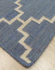 Alluring Bianca Blue Flatweave Wool Rug, a blend of cool blues and creamy whites creating a serene, subtly textured floor covering, displayed in a bright living room setting.