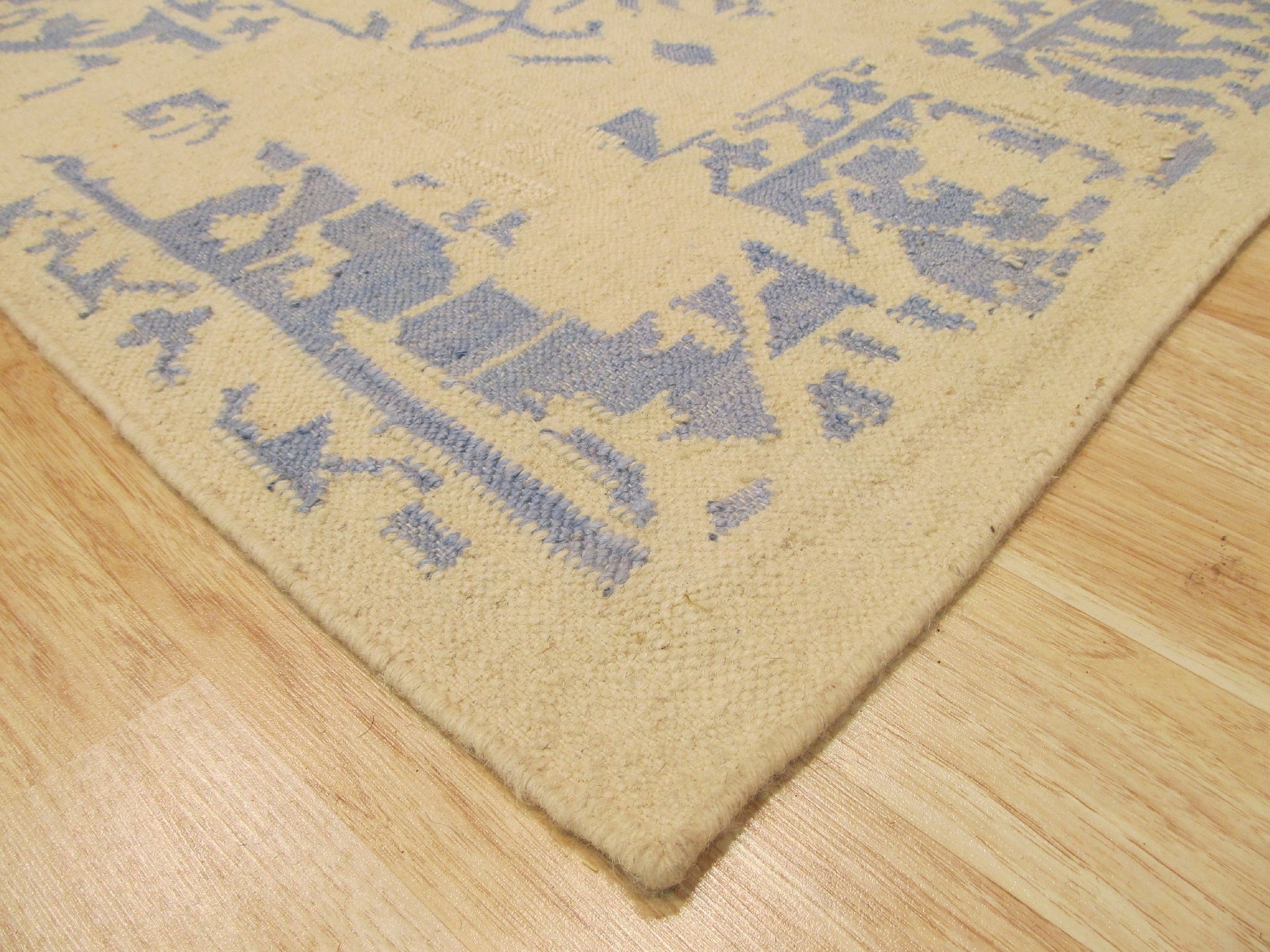 Stylish Graceful Blue Flatweave Wool Rug, showcasing its cool blue hues and flatweave construction, complements a modern living room with warm wood floors and a sleek sofa.