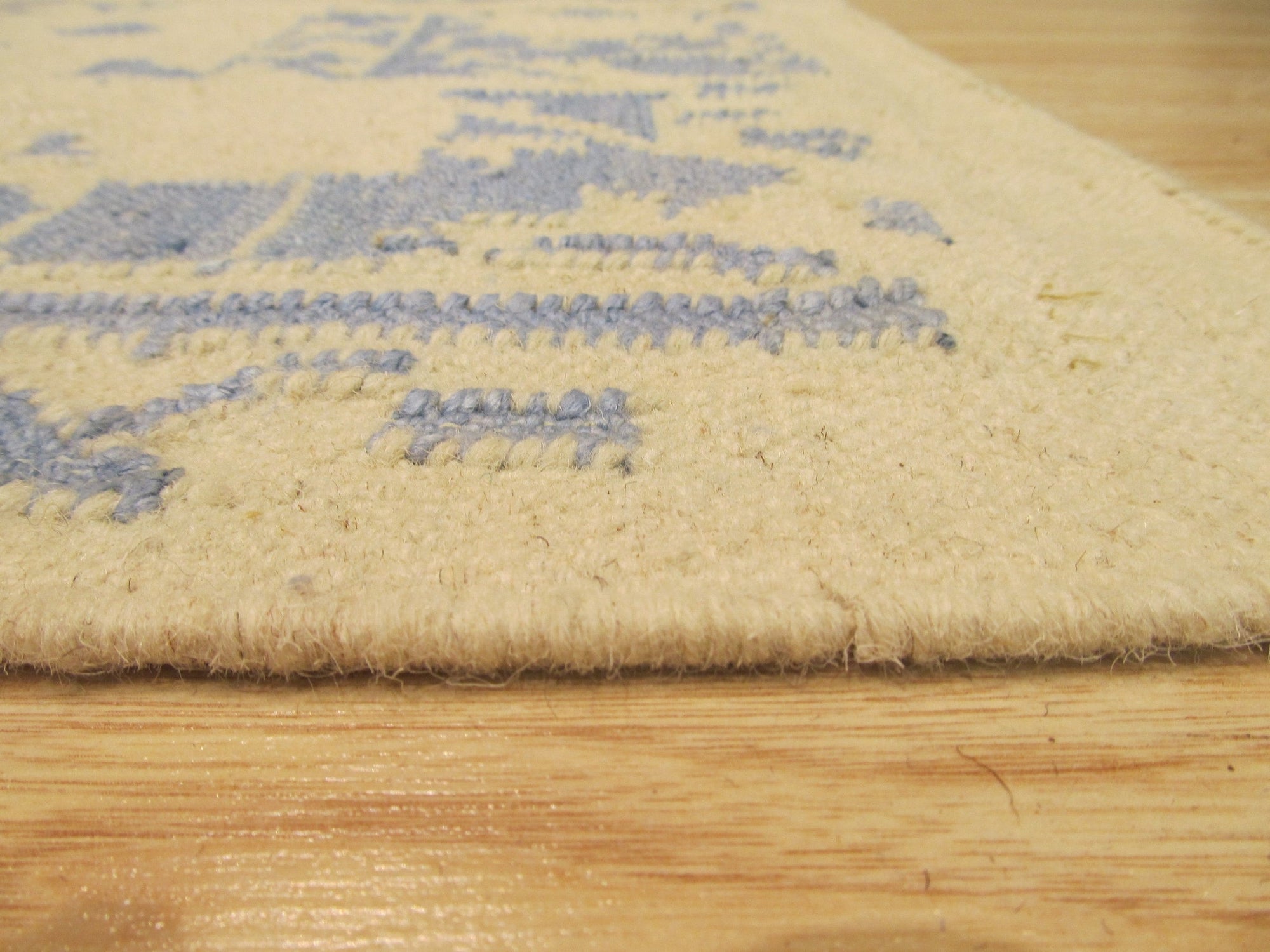 Stylish Graceful Blue Flatweave Wool Rug in a living room setting, its cool blue tones anchoring a seating area with mid-century modern furniture. Soft light highlights the flatweave construction and subtle texture.