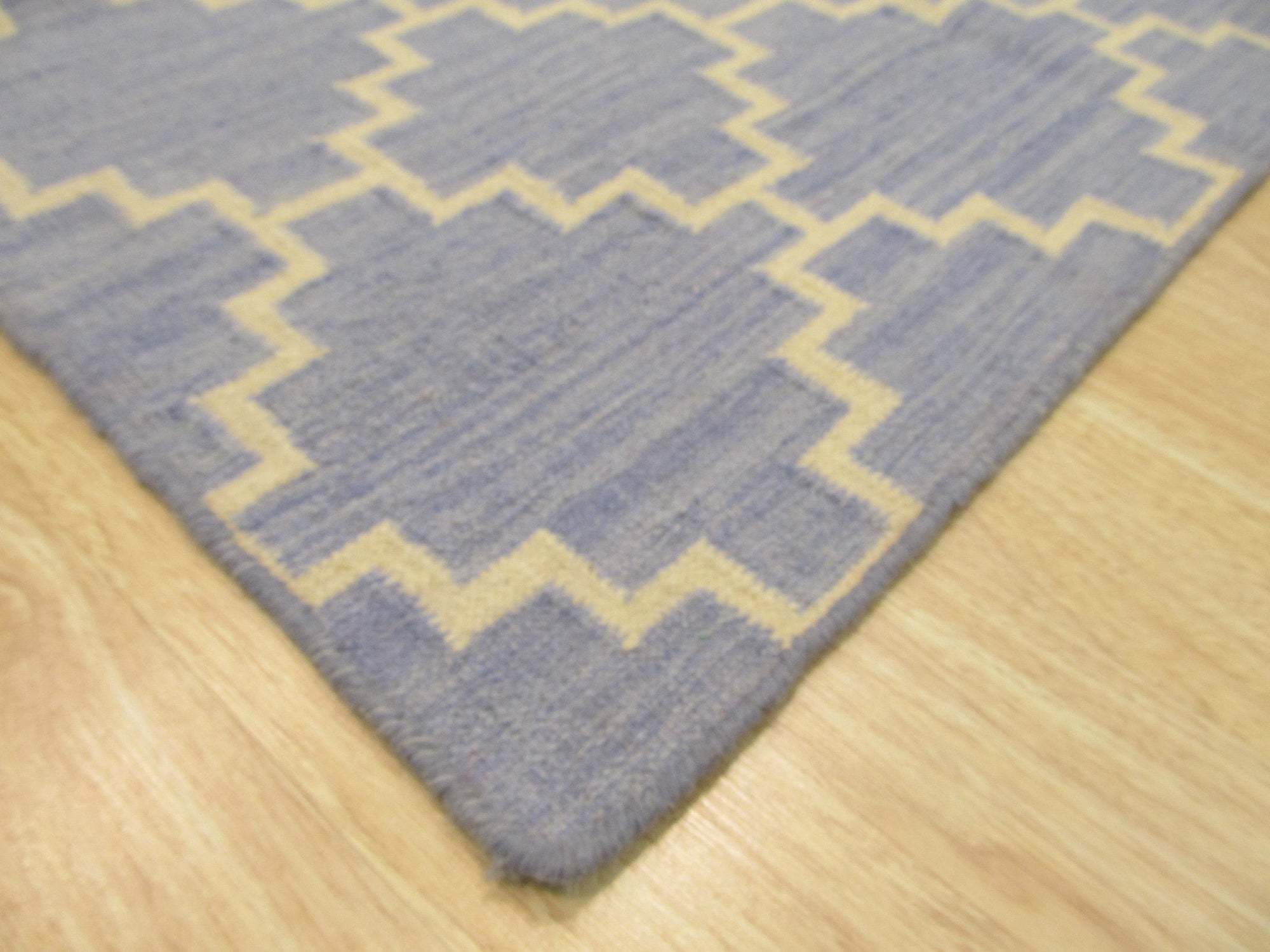 Ruby Moroccan Blue Flatweave Wool Rug, blending deep blues and intricate patterns in a flatweave wool construction, anchors a softly lit living space.