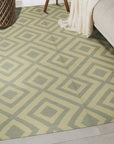 Quinn Kilim Beige Flatweave Wool Rug displayed in a bright living room setting. Warm, neutral tones and geometric patterns define this beige wool rug. A coffee table sits atop, anchoring the space and hinting at a comfortable, lived-in feel.