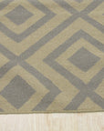 Quinn Kilim Beige Flatweave Wool Rug, featuring geometric patterns in neutral beige tones, layered atop a dark wood floor in a bright living space.