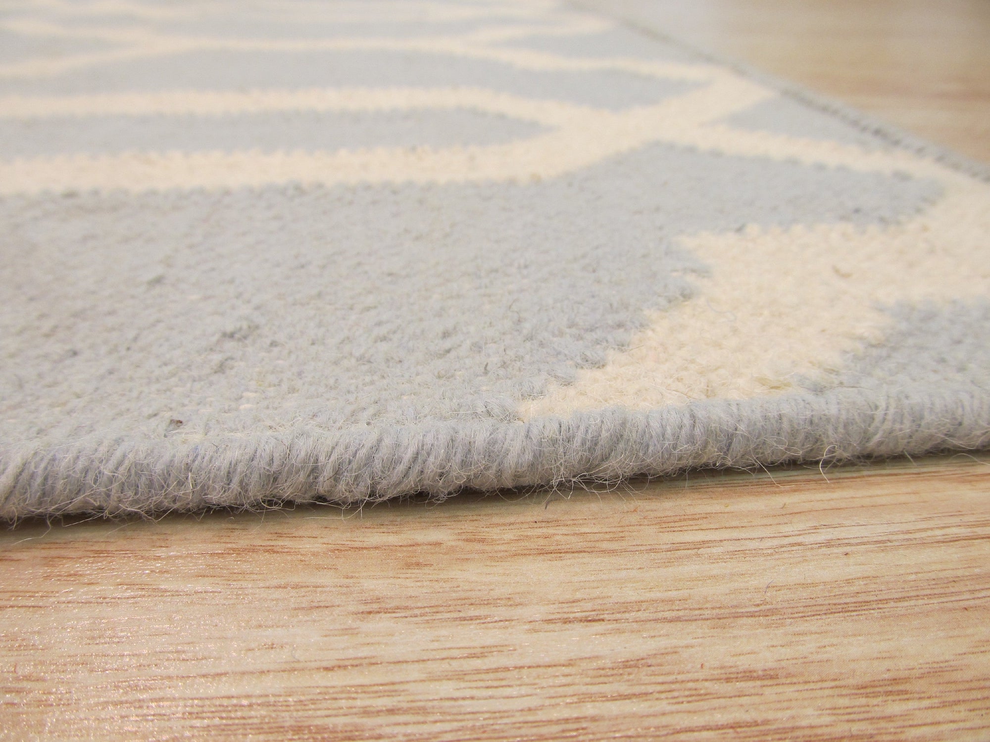 Chloe Trellis Blue Flatweave Wool Rug, its soft blue and cream trellis pattern grounding a bright, airy room. Natural light highlights the wool's subtle texture.