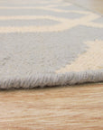 Chloe Trellis Blue Flatweave Wool Rug, its soft blue and cream trellis pattern grounding a bright, airy room. Natural light highlights the wool's subtle texture.
