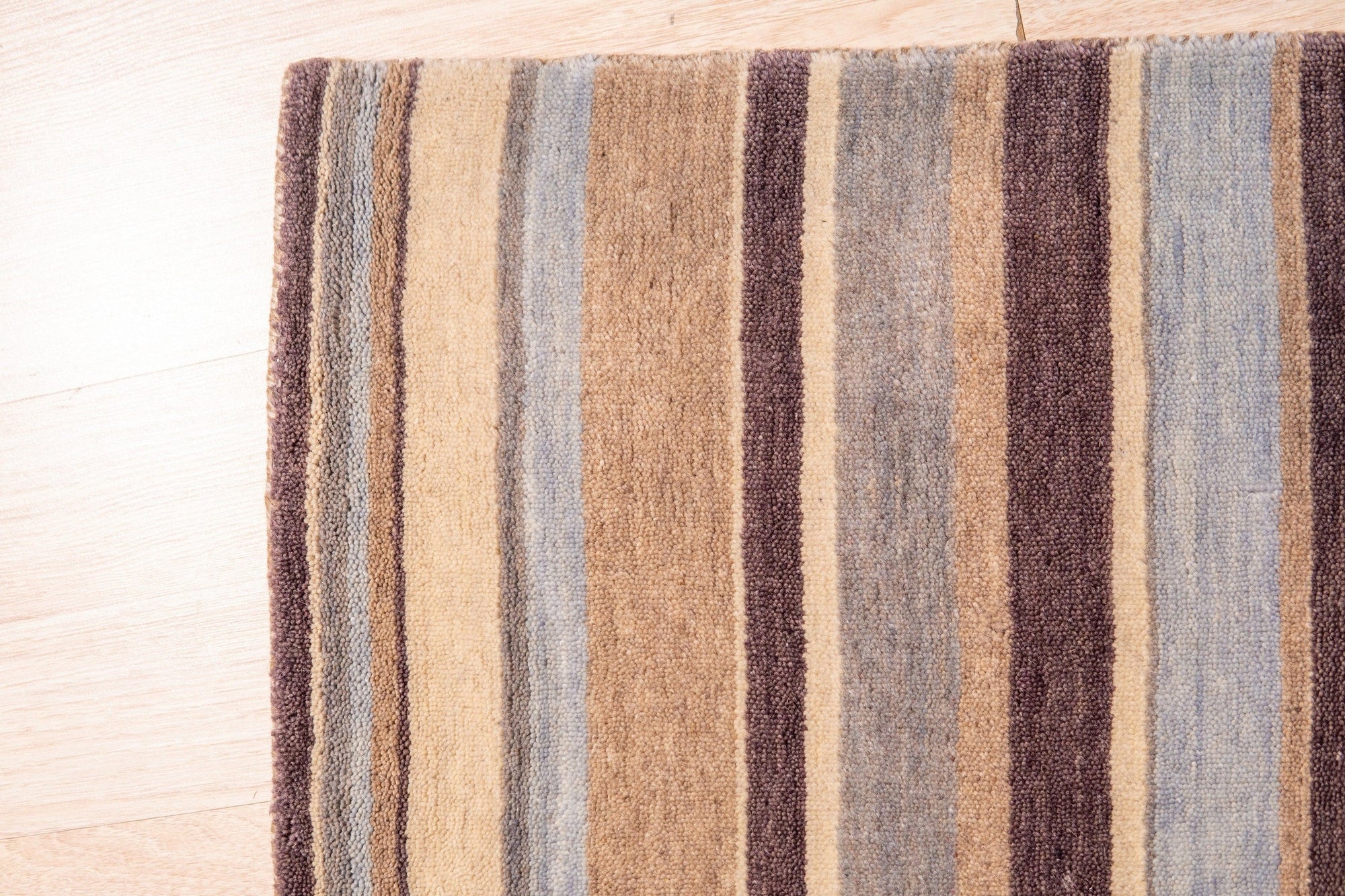 Luxurious Willow Multicolor Handmade Wool Rug sprawls invitingly on a light wood floor, its vibrant blues, greens, creams, and browns creating a rich, textured landscape underfoot.