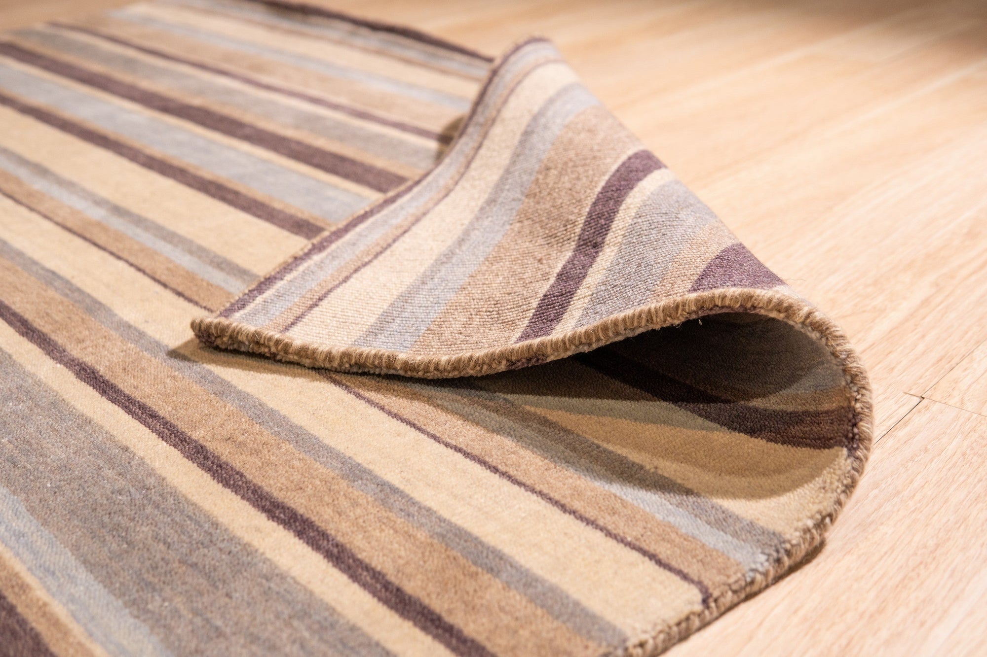 Luxurious Willow Multicolor Handmade Wool Rug, showcasing a vibrant blend of earthy tones and intricate patterns, lies flat on a hardwood floor, its soft texture inviting touch in a warmly lit room.