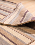 Luxurious Willow Multicolor Handmade Wool Rug, showcasing a vibrant blend of earthy tones and intricate patterns, lies flat on a hardwood floor, its soft texture inviting touch in a warmly lit room.
