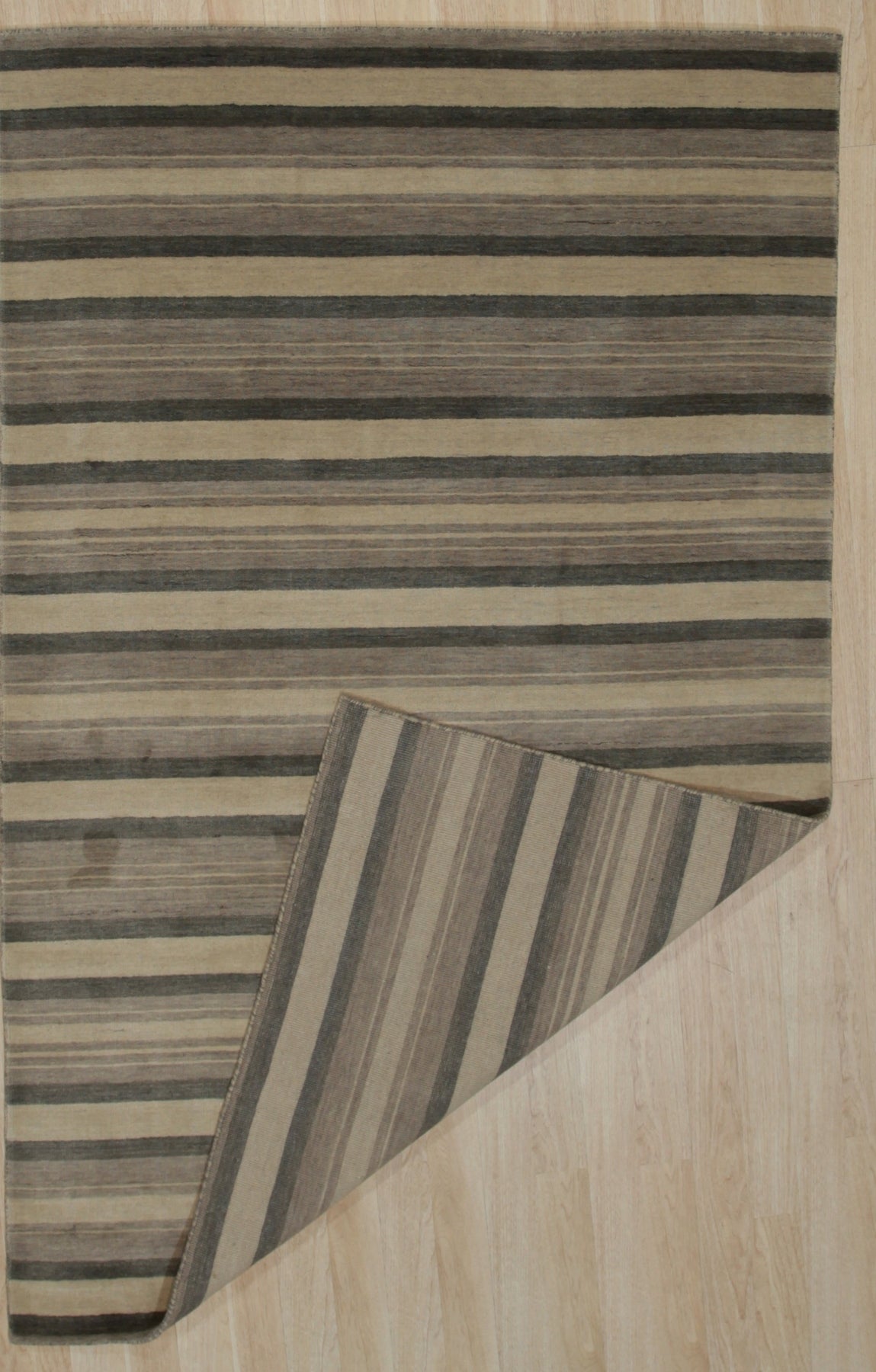 Serene Striped Multicolor Handmade Wool Rug gracing a light wood floor, its vibrant stripes of teal, mustard, cream, and charcoal lending a modern, geometric touch to the minimalist space.