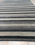Serene Striped Multicolor Handmade Wool Rug, a handcrafted wool rug featuring vibrant stripes of varying widths in warm and cool tones, creating a textured and inviting floor covering within a contemporary living space.