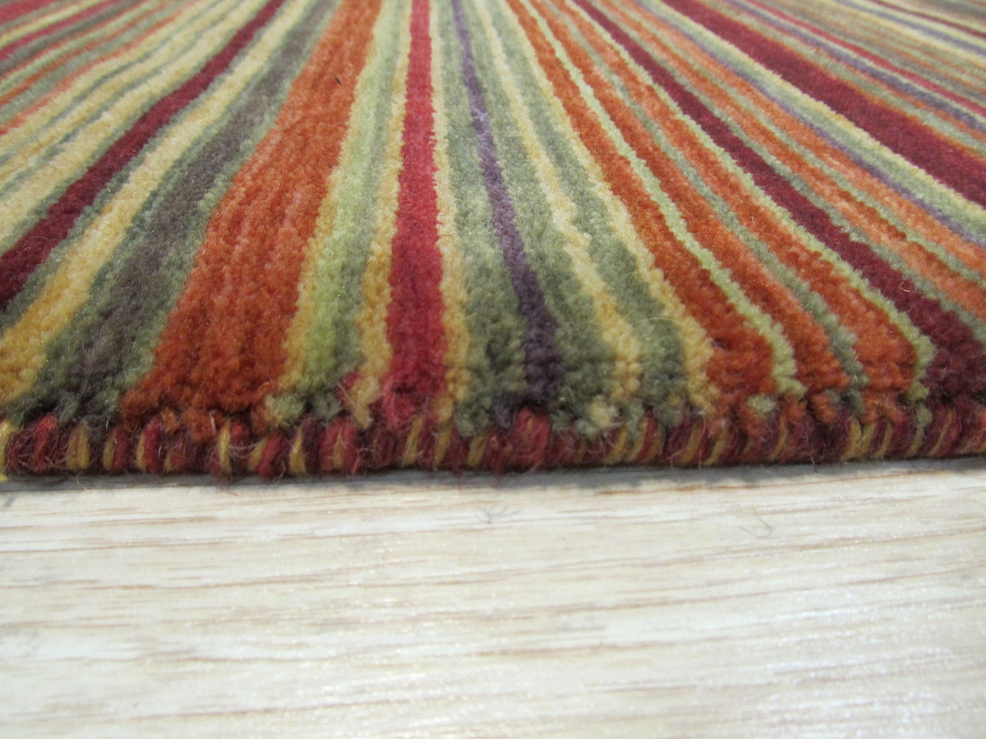 Lush Striped Red Flatweave Wool Rug anchoring a living space, its bold red stripes adding warmth and texture to the scene. Flatweave construction apparent in the tightly woven wool fibers.