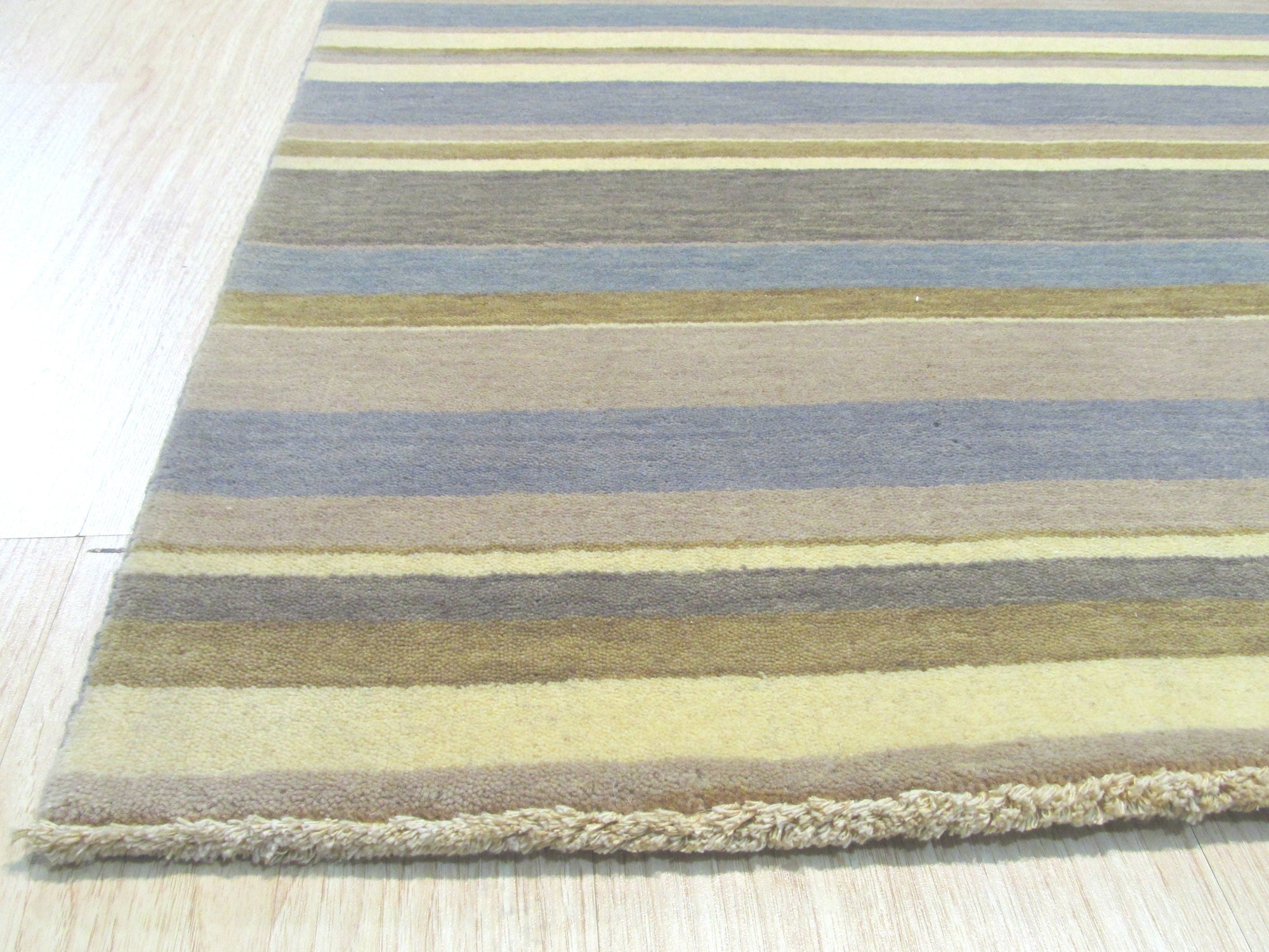 Ella Rustic Brown Handmade Wool Rug, showcasing warm, earthy tones and hand-woven texture, complements a modern living room setting with a neutral sofa and wooden accents.
