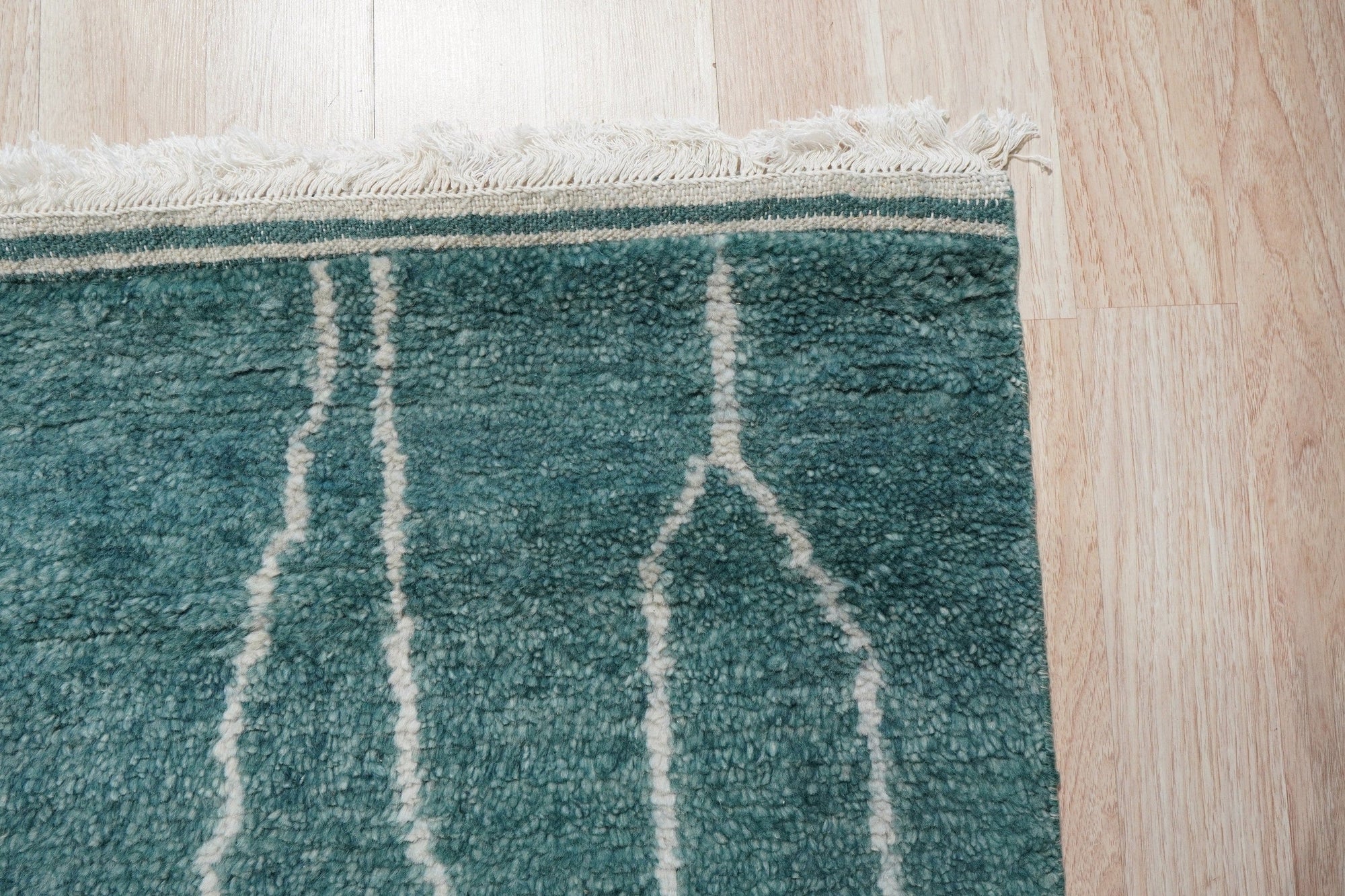Beautiful Celia Green Hand Knotted Wool Rug, its lush green hues and intricate hand-knotted wool texture enriching a warmly lit living space; positioned as a vibrant foundation beneath contemporary furniture.