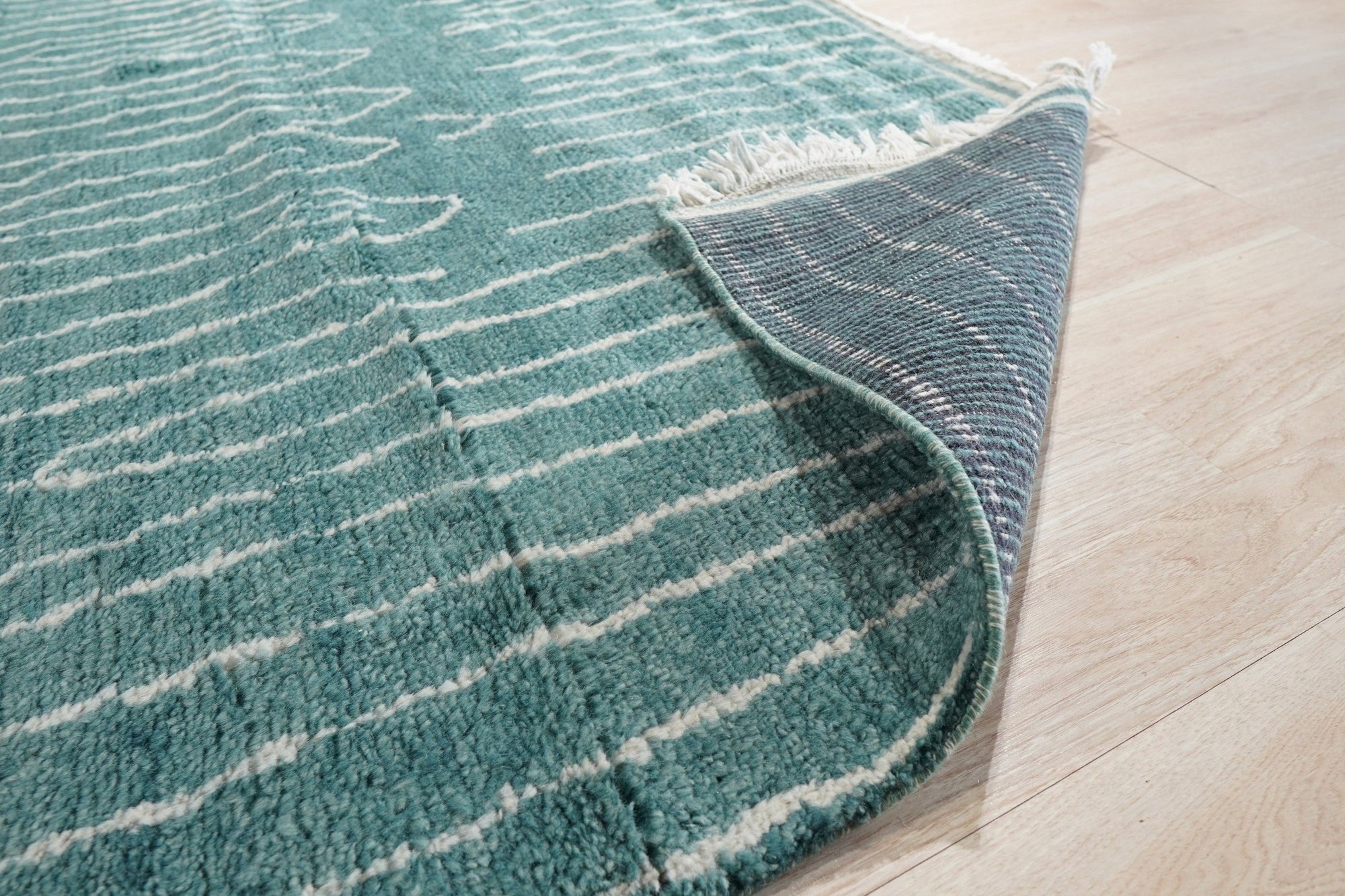 Beautiful Celia Green Hand Knotted Wool Rug, its hand-knotted texture visible in a close-up shot. Deep greens and subtle variations in the wool create a luxurious feel.