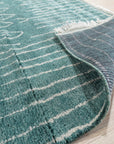 Beautiful Celia Green Hand Knotted Wool Rug, its hand-knotted texture visible in a close-up shot. Deep greens and subtle variations in the wool create a luxurious feel.