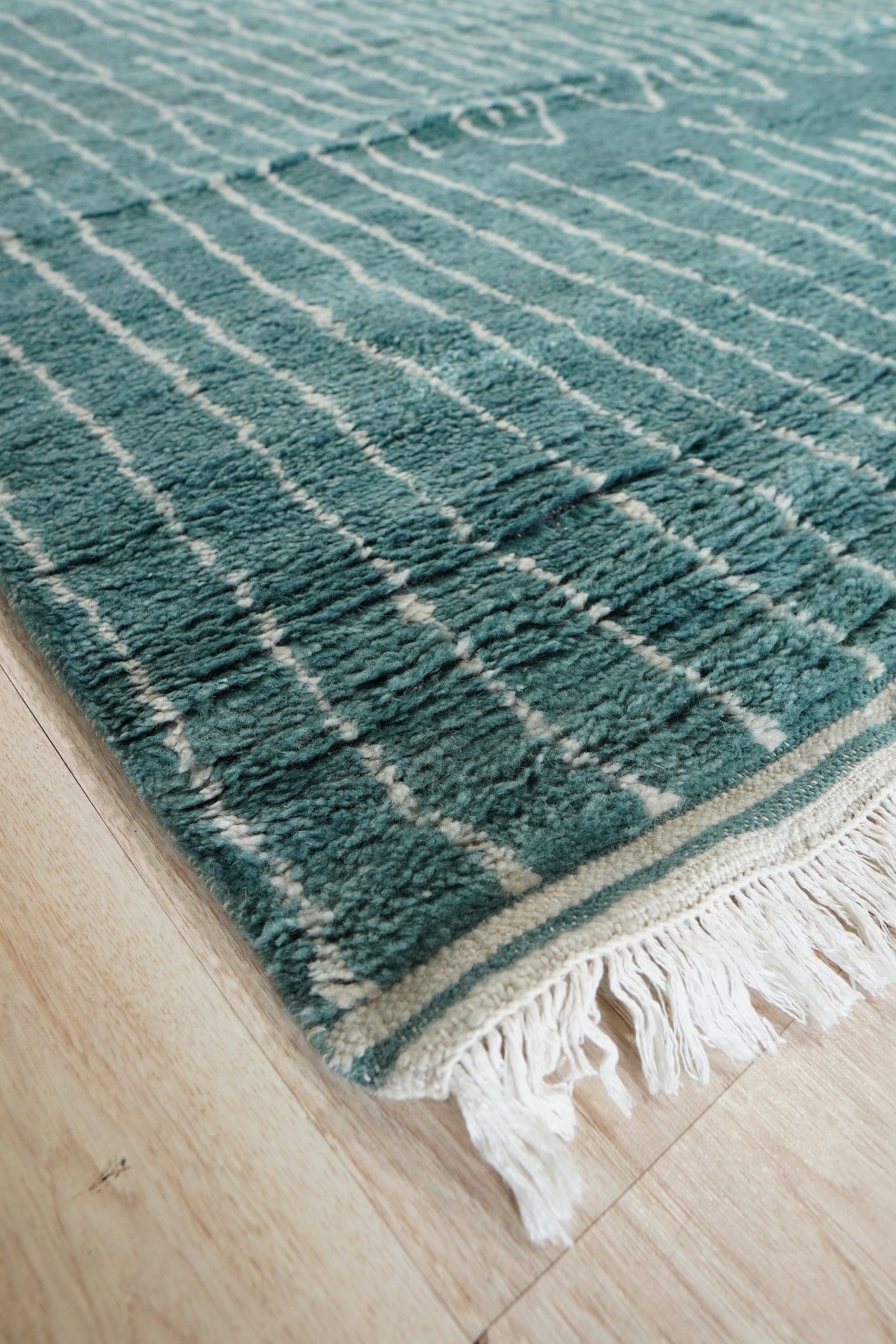 Hand-knotted texture of the Beautiful Celia Green Hand Knotted Wool Rug fills the frame, showcasing its intricate weave and vibrant green hues. Wool fibers catch the light, highlighting the rug's plush pile and detailed design.