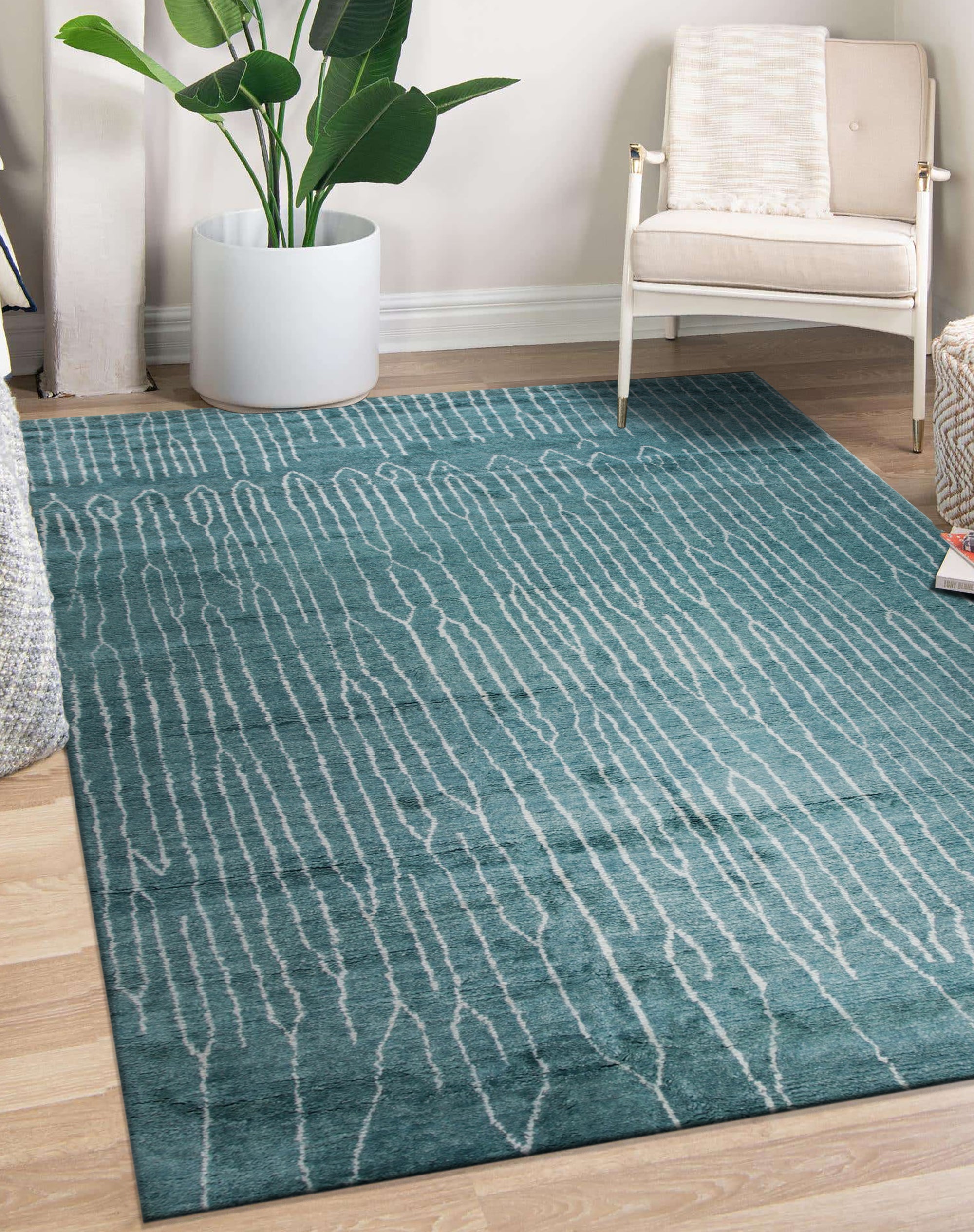 Beautiful Celia Green Hand Knotted Wool Rug, showcasing an intricate, textural floral pattern in shades of green, ivory, and subtle brown, lies flat on a light hardwood floor, its hand-knotted wool pile adding warmth and sophistication to a bright, airy space.