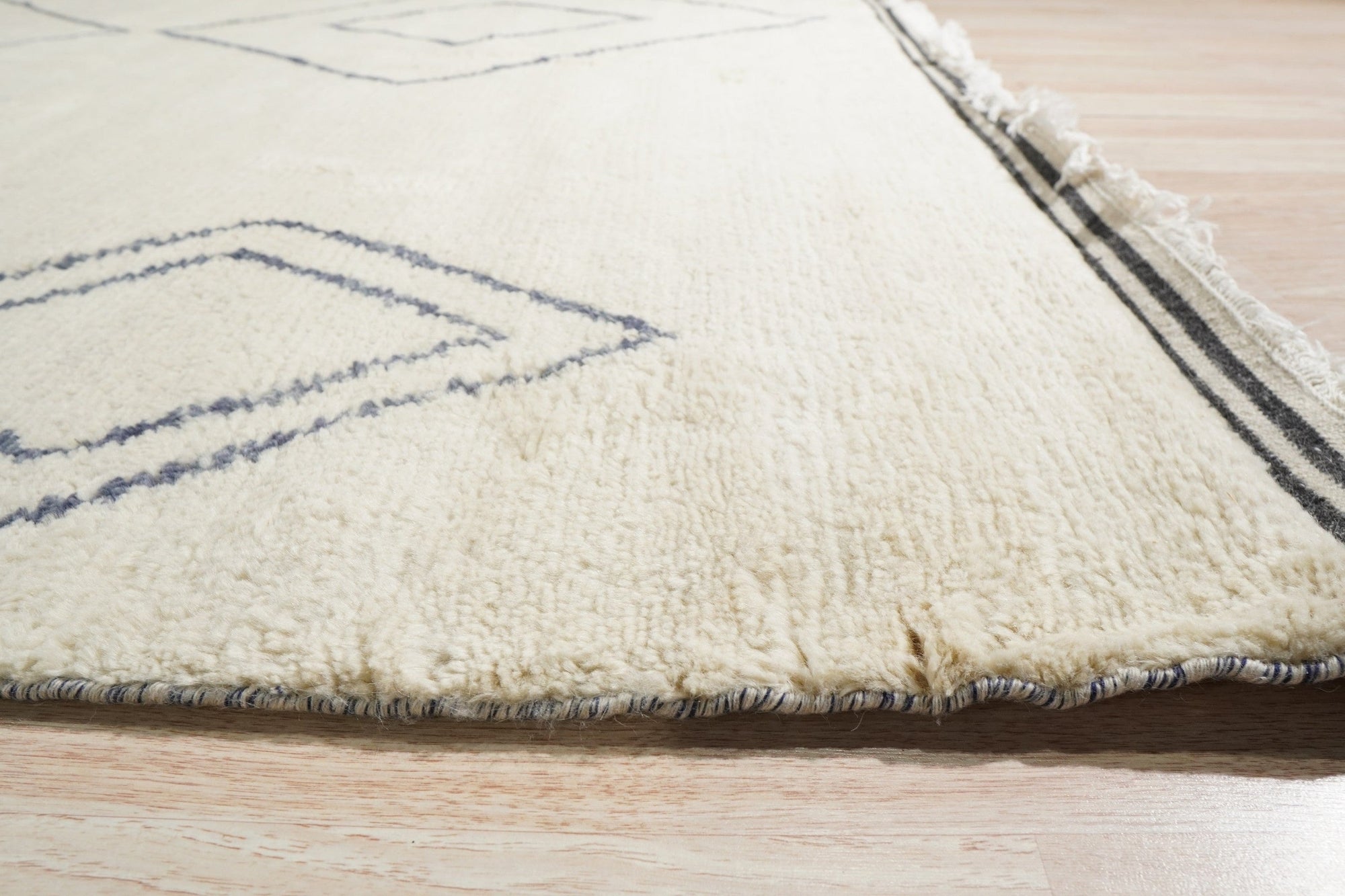 Selene Moroccan Ivory Hand Knotted Wool Rug, its geometric design adding warmth and texture to a sun-drenched living room. Soft ivory wool pile invites bare feet, contrasting beautifully with dark wood flooring.