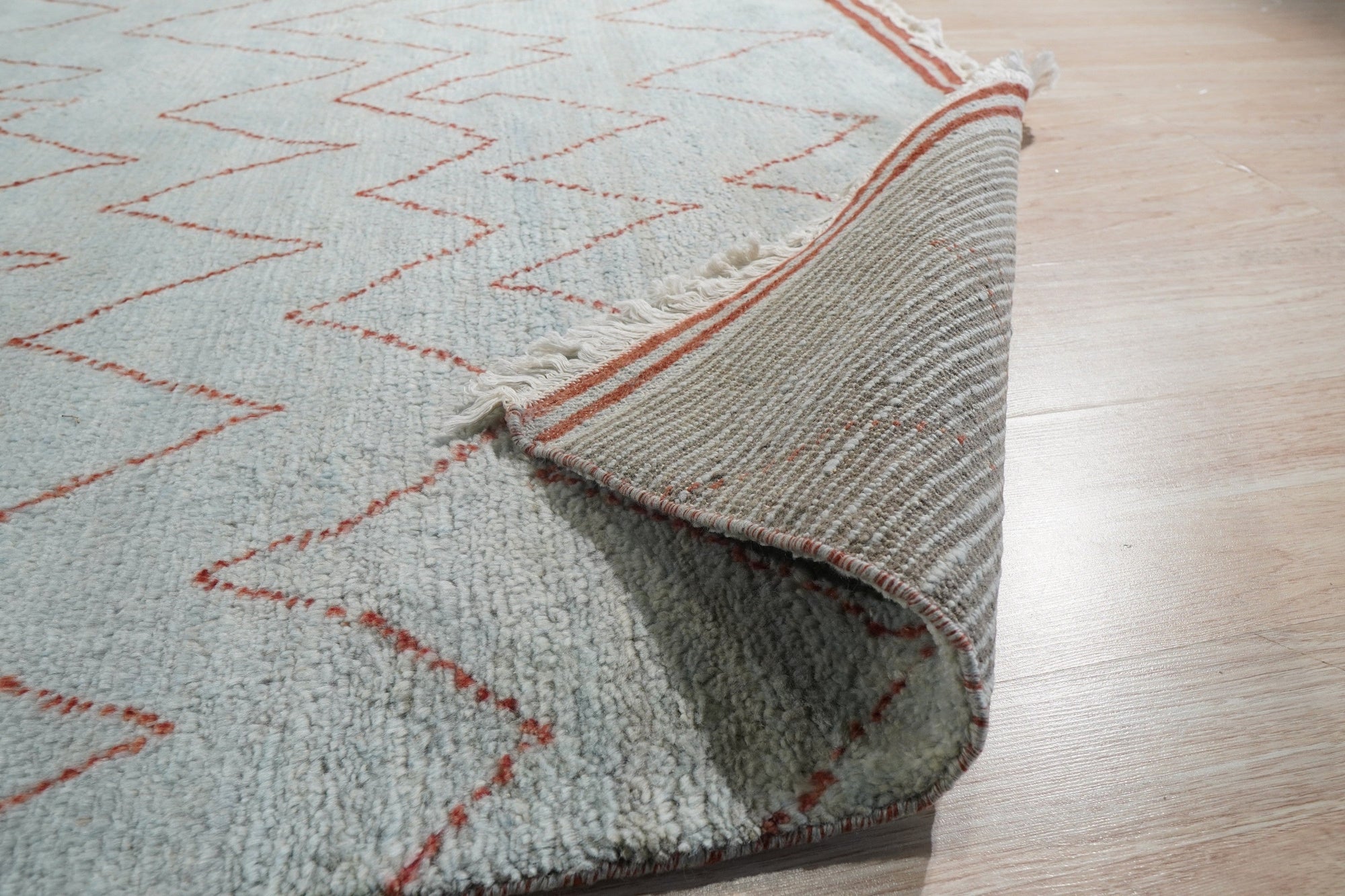 Isla Moroccan Blue Hand Knotted Wool Rug, showcasing a richly textured field of deep blues and creamy whites in a traditional Moroccan design, lies gracefully on a hardwood floor, adding warmth and character to the room.
