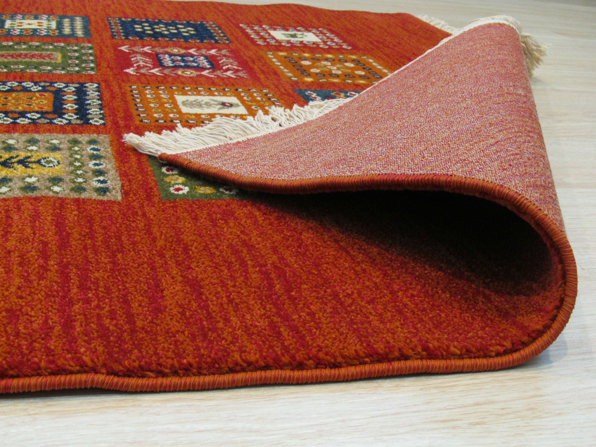 Classic Artisan Red Machine Made Wool Rug: Crimson and ivory geometric patterns dance across this machine-made wool rug, filling a brightly lit room with warmth and texture.
