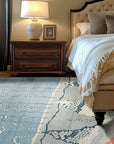 Comfortable Moroccan Multicolor Hand Knotted Wool Rug, its vibrant palette and intricate geometric patterns radiating warmth, rests atop a light wood floor, bathed in soft, natural light.