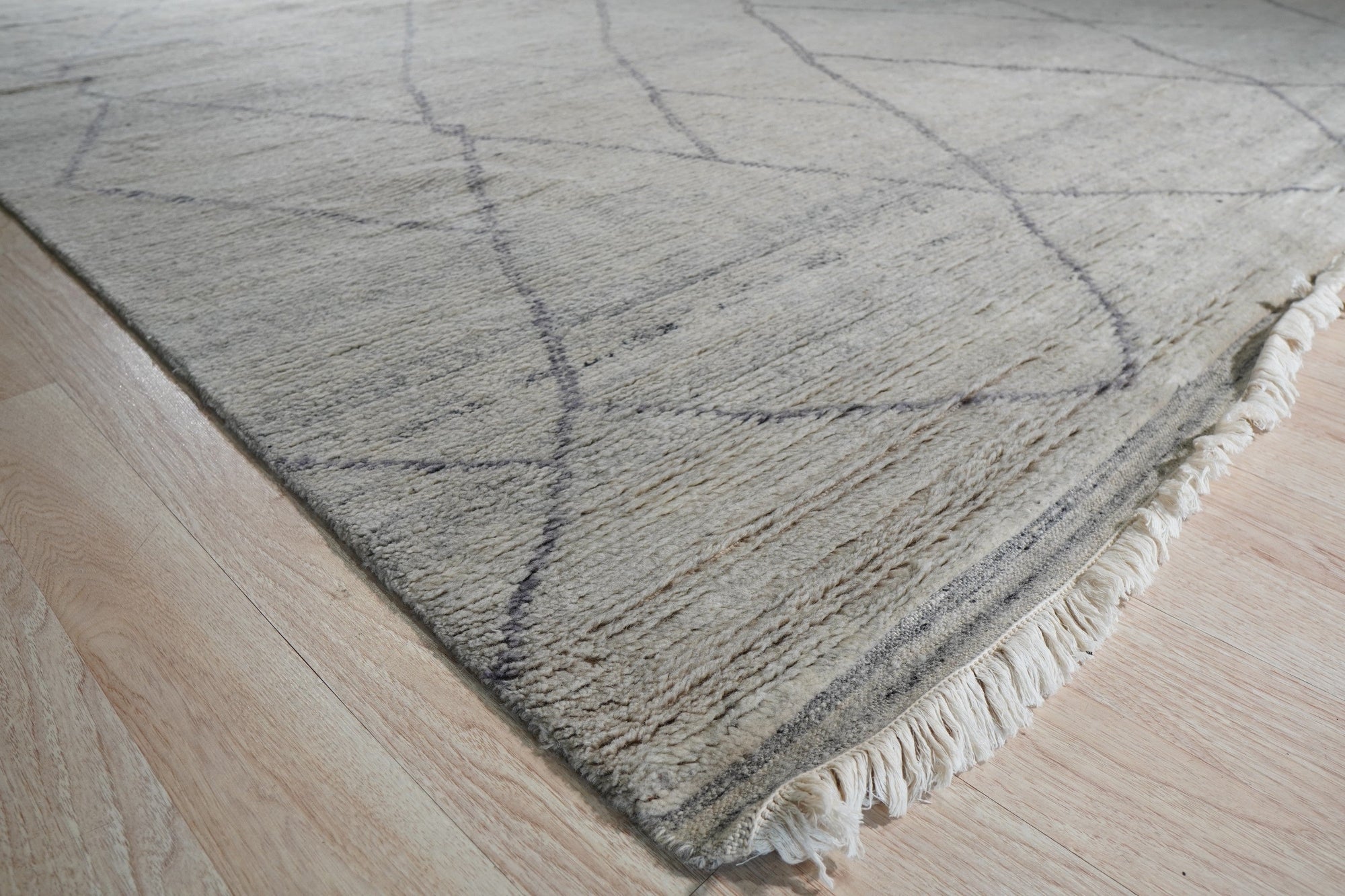 Penelope Diamond Silver Hand Knotted Wool Rug, a shimmering silver wool rug with a classic diamond pattern, gracing a well-lit living space.