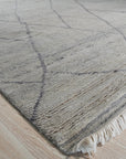 Penelope Diamond Silver Hand Knotted Wool Rug, a shimmering silver wool rug with a classic diamond pattern, gracing a well-lit living space.