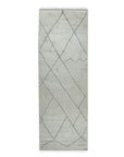 Penelope Diamond Silver Hand Knotted Wool Rug, showcased in a bright, airy living room setting. Its subtle silver and neutral tones complement the modern furniture, highlighting the intricate hand-knotted diamond pattern across the soft wool fibers.