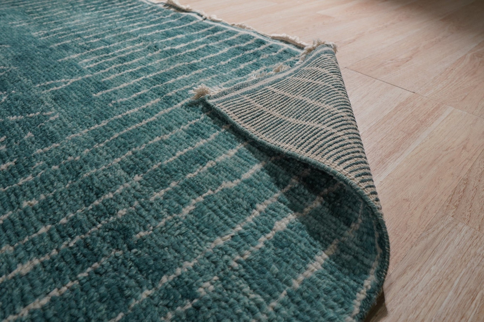 Lush Moroccan Green Hand Knotted Wool Rug, its vibrant emerald and olive tones enriching a sun-drenched living room, hand-knotted wool construction apparent in the textured pile underfoot.