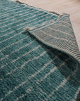 Lush Moroccan Green Hand Knotted Wool Rug, its vibrant emerald and olive tones enriching a sun-drenched living room, hand-knotted wool construction apparent in the textured pile underfoot.