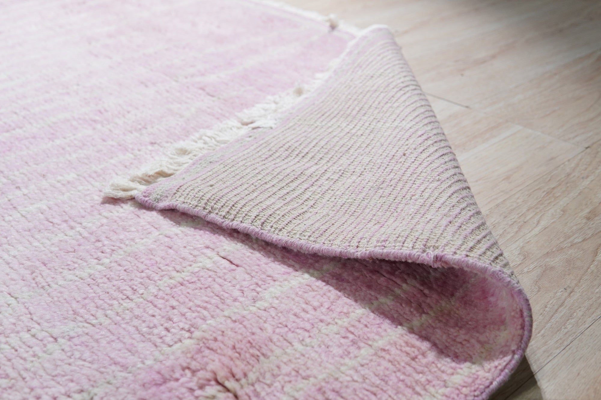 Delicate Moroccan Pink Hand Knotted Wool Rug, seen in a styled interior, its subtle pink hues and hand-knotted texture lending warmth and a touch of bohemian elegance to the space.