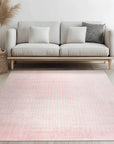 Delicate Moroccan Pink Hand Knotted Wool Rug, a soft pink hand-knotted wool rug featuring geometric patterns, seen on a light wooden floor partially covered by the rug, showing subtle variations in color and texture.