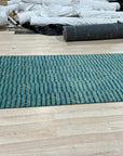 Exquisite Moroccan Handmade Wool Green Rug, its textured pile vibrant emerald and moss, lies centered in a sunlit room, intricate geometric patterns adding warmth and character to the hardwood floor.