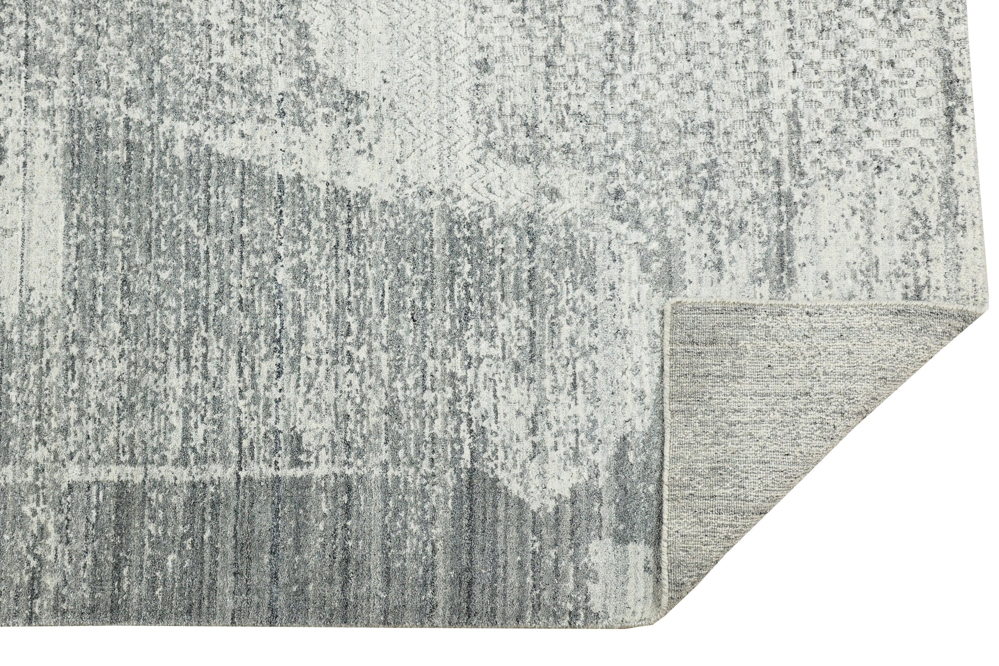 Versatile Freya Gray Handmade Wool Rug, a textural landscape in soft grays, anchors a bright, airy living space with comfortable seating and natural light filtering through sheer curtains.