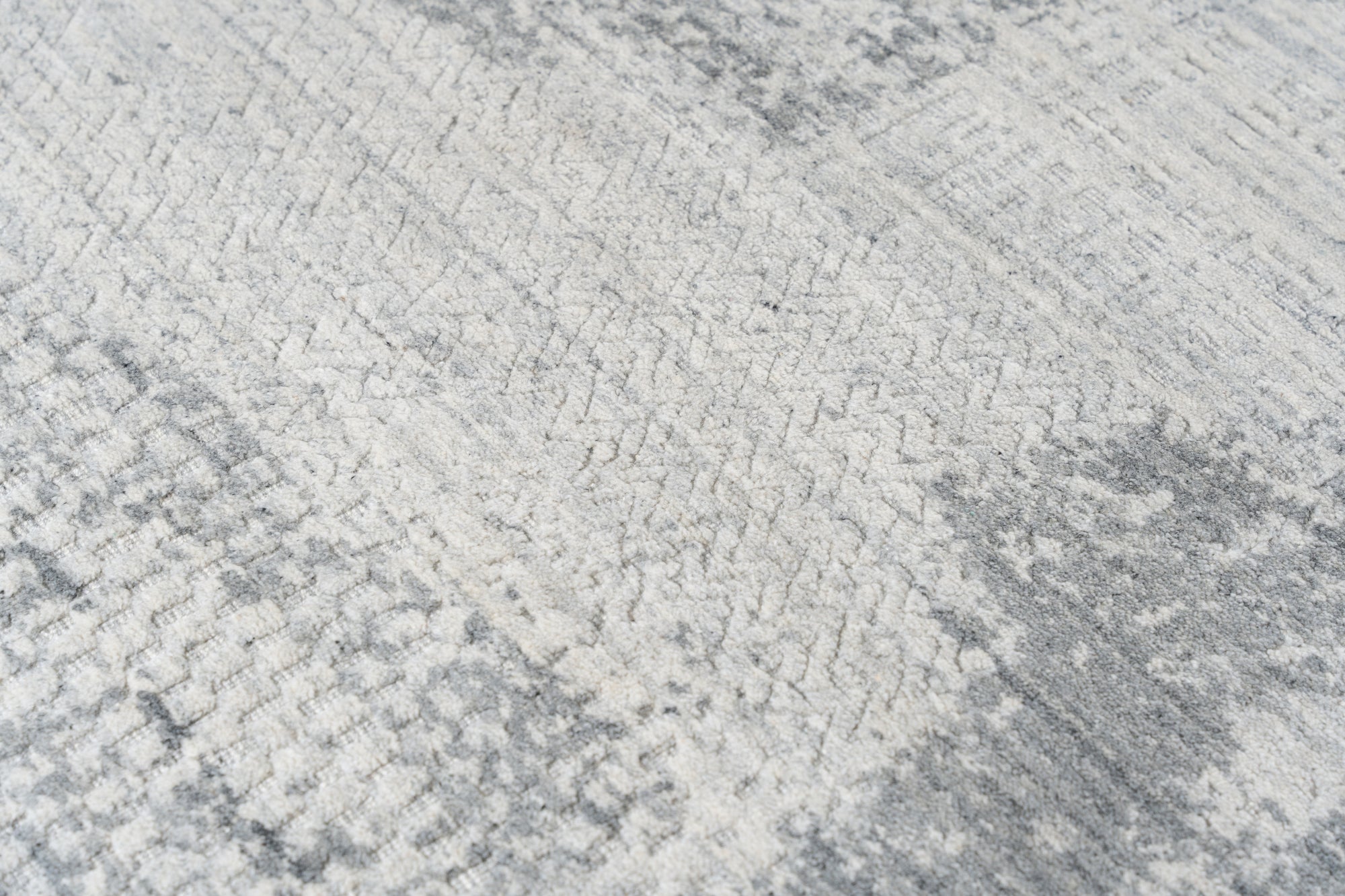 Versatile Freya Gray Handmade Wool Rug, a gray wool rug with a subtle geometric pattern, displayed in a bright, modern living room setting, softening the space with texture and muted tones.