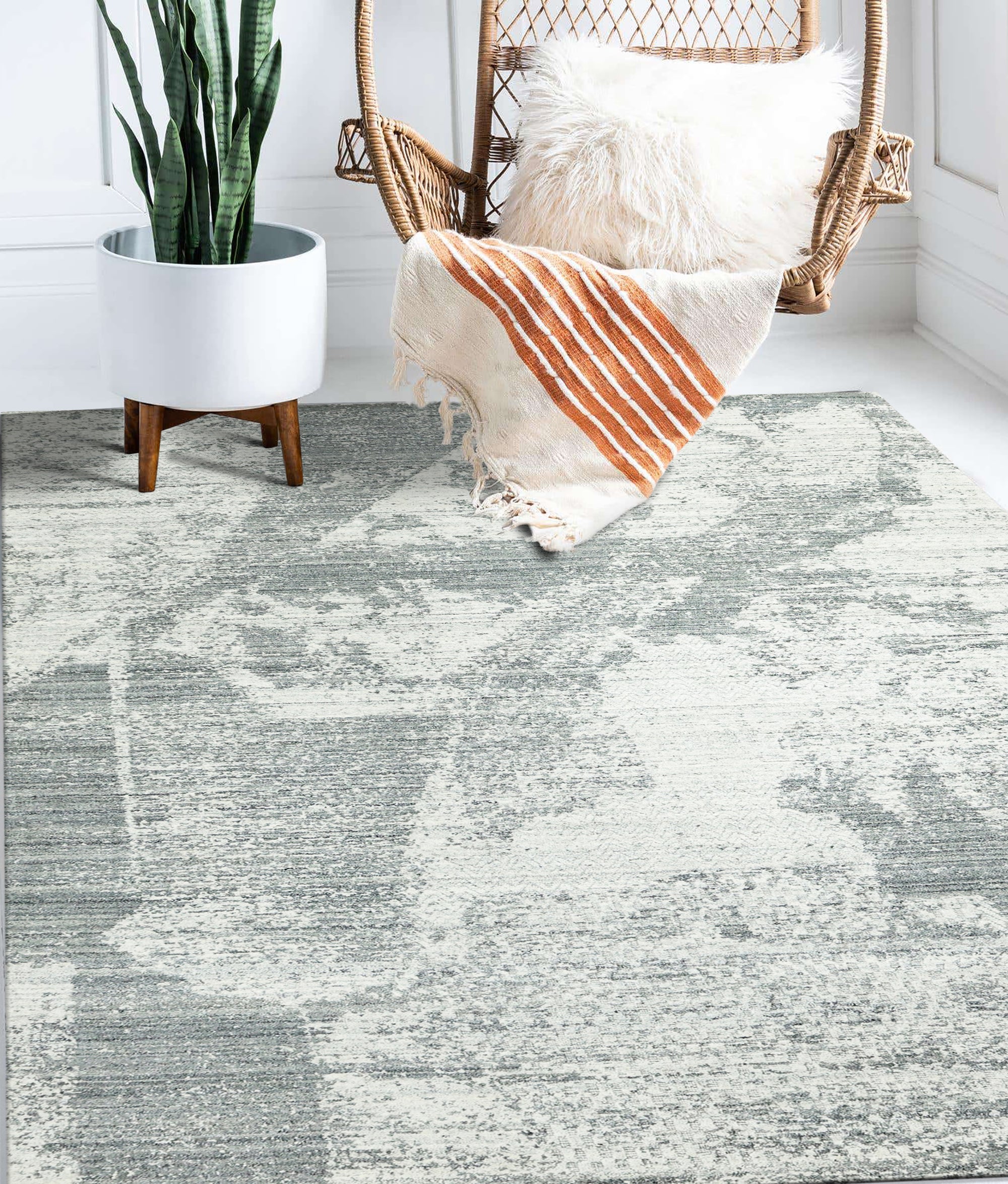 Versatile Freya Gray Handmade Wool Rug displayed on a light hardwood floor, its textured, neutral gray wool fibers offering subtle visual interest; sunlight highlights the handcrafted quality and subtle variations in the pile.