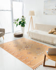 Fiona Penelope Coral Flatweave Rug, a soft coral-toned flatweave rug with subtle geometric patterns, adding warmth and texture to a brightly lit living room setting.