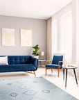 Rustic Penelope Silver Flatweave Rug displayed in a modern living room setting; light reflects off the rug's flat weave, highlighting its silver and neutral tones, complementing the surrounding furniture.