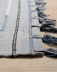 Rustic Penelope Silver Flatweave Rug, a shimmering silver flatweave rug with subtle variations in tone and texture, seen in a bright, airy living space suggesting comfort and contemporary style.