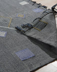 Sleek Inviting Gray Flatweave Rug layered over light hardwood flooring in a bright, modern living room; texture and subtle pattern are visible in the gray flatweave.