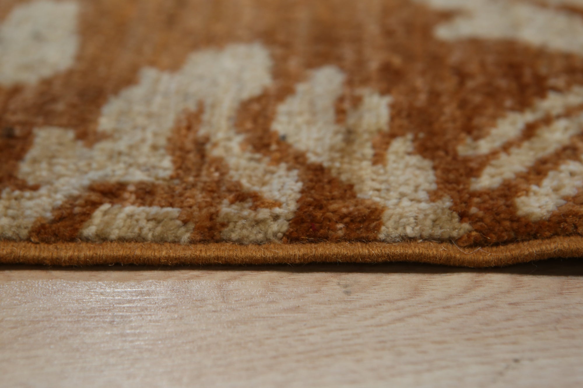 Refined Bespoke Brown Hand Knotted Afghan Wool Rug, showcasing rich brown tones and intricate hand-knotted detailing, lies flat on a light wood floor, offering a textural contrast and sophisticated warmth to the space.