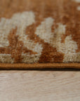 Refined Bespoke Brown Hand Knotted Afghan Wool Rug, showcasing rich brown tones and intricate hand-knotted detailing, lies flat on a light wood floor, offering a textural contrast and sophisticated warmth to the space.