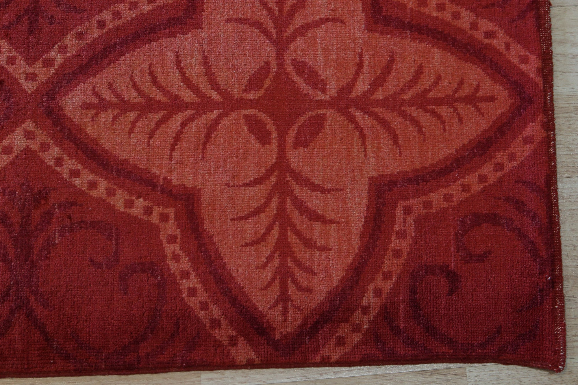 Penelope Maya Red Hand Knotted Afghan Wool Rug, vibrant red hand-knotted wool rug with intricate geometric patterns, displayed on a light wood floor.