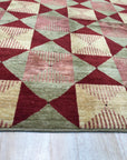 Sloane Diamond Red Hand Knotted Afghan Wool Rug, showcasing intricate diamond patterns woven in rich red Afghan wool, graces a softly lit interior.